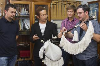 Os irmáns Alfonso (esquerda) e Xosé Gil (dereita) entregan a súa gaita ao xaponés Yuki Kojima en presenza do gaiteiro Xosé Manuel Budiño. Foto: Lalo R. Villar.