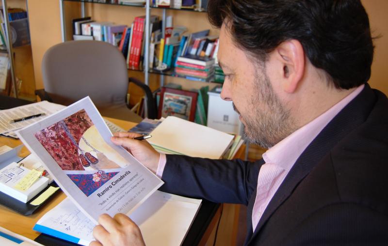 El secretario xeral da Emigración, con el cartel de la exposición de Ramiro Cimadevila que se podrá visitar en la Xuventude de Galicia - Centro Galego de Lisboa del 13 de mayo al 3 de junio