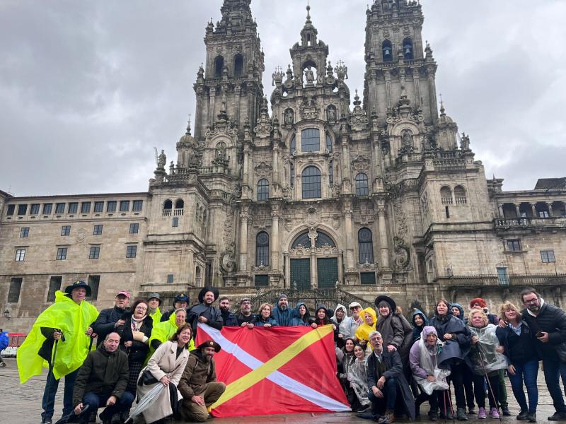 Imagen de la llegada a la Praza do Obradoiro de las y los miembros de la Irmandade Galega de Rubí que peregrinaron a Compostela
